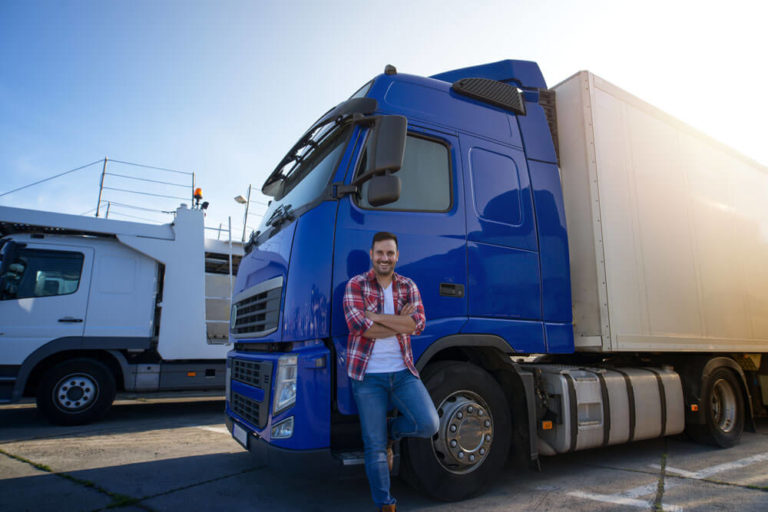An image of a man standing outside of a semi truck covered by truck insurance.