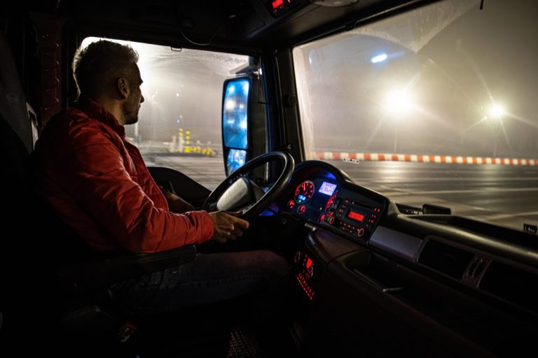 An image of a man sitting inside the cab of a semi truck.